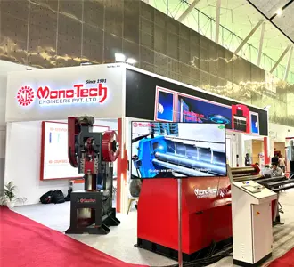MonoTech Engineers Pvt Ltd plate rolling machine and industrial press brake on display at a machinery exhibition booth.